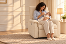 AI-staged lifestyle image of a mum bottle-feeding her baby in the Rever Bebe Ollie Ivory nursery chair