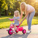 Toddler tricycle in pink with a sturdy metal frame, featuring a rear storage basket for toys and snacks during outdoor play.